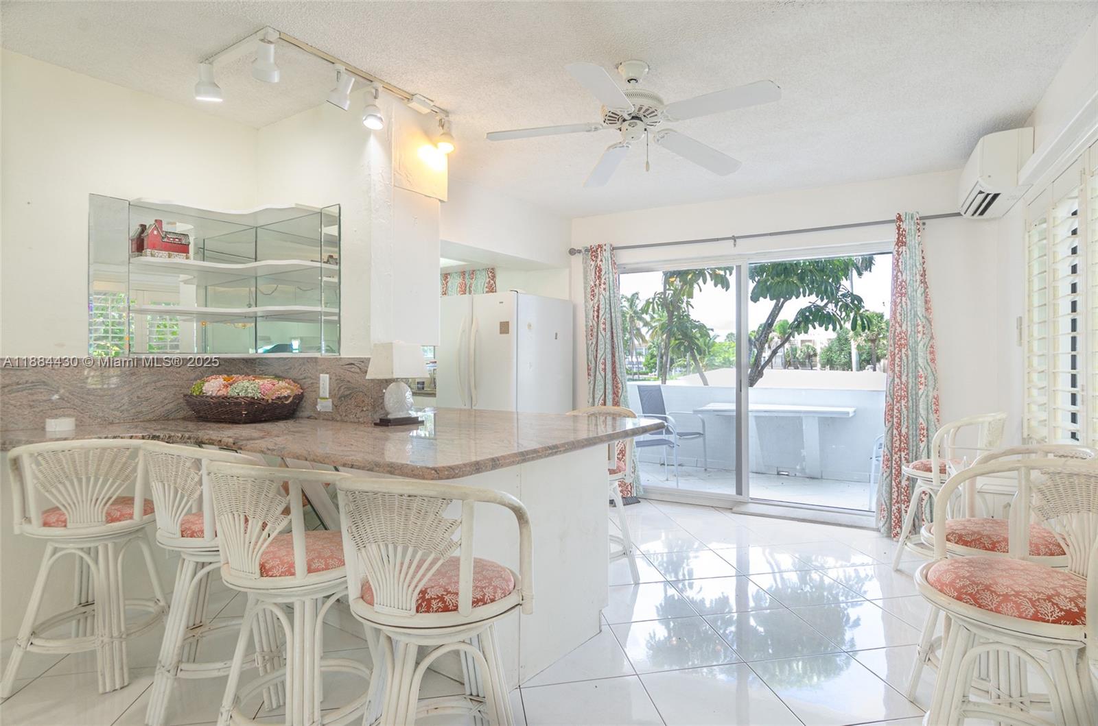 A kitchen with a granite breakfast bar, white wicker stools, and a sliding glass door — 1470 S Ocean Blvd # 702, Pompano Beach FL 33062, POMPANO BEACH, FL