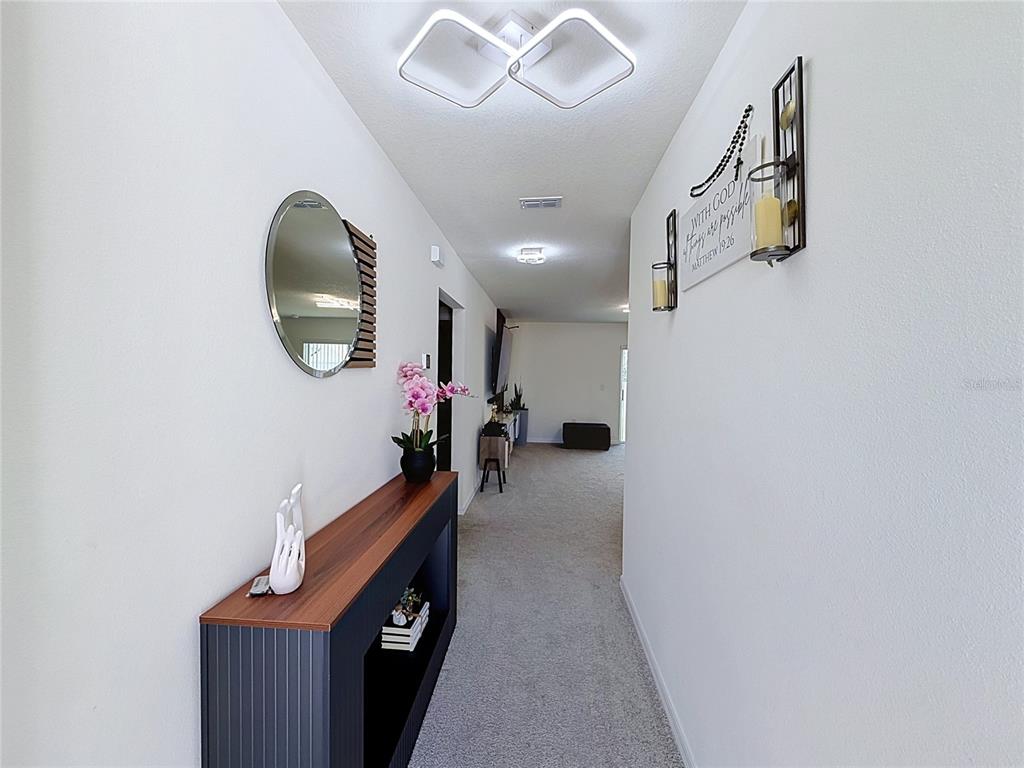 A hallway features a console table, a round mirror, and wall-mounted decor under modern lighting — 339 TOWNS CIRCLE, HAINES CITY, FL