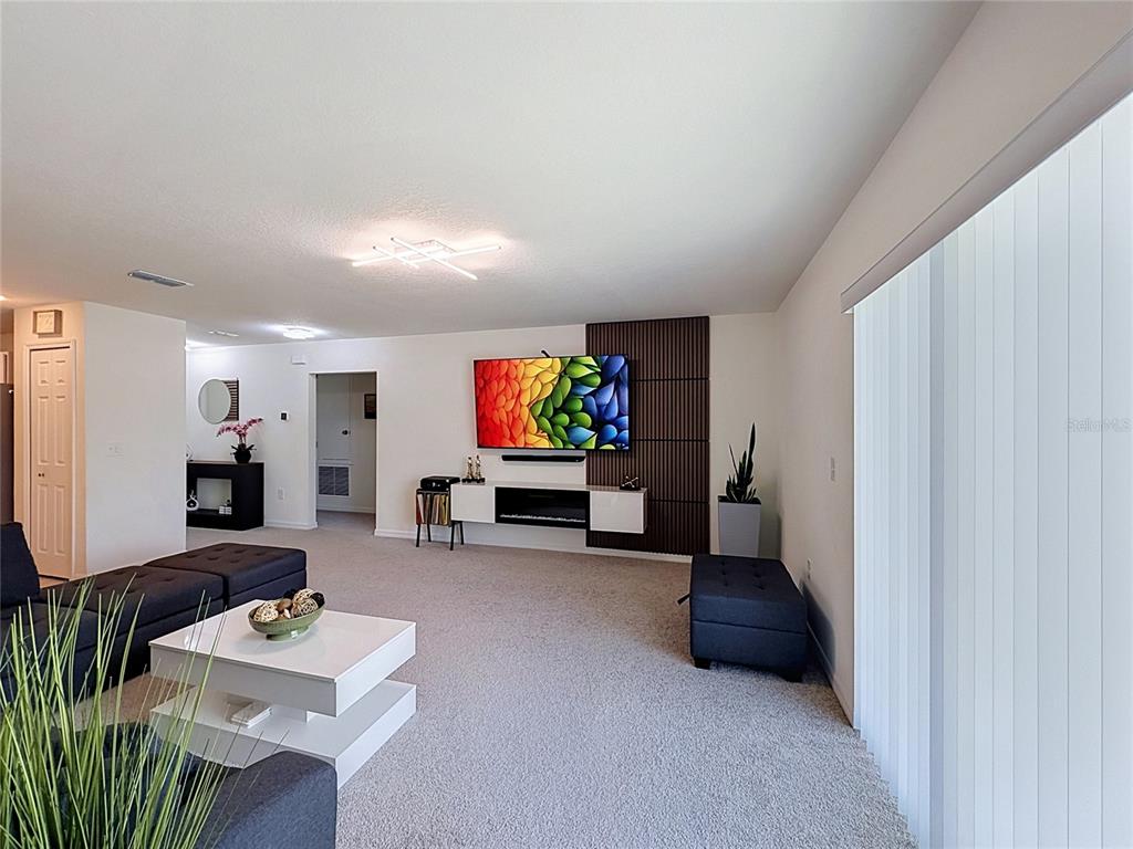 A living room features a wall-mounted television, a fireplace console, and gray carpeted flooring — 339 TOWNS CIRCLE, HAINES CITY, FL
