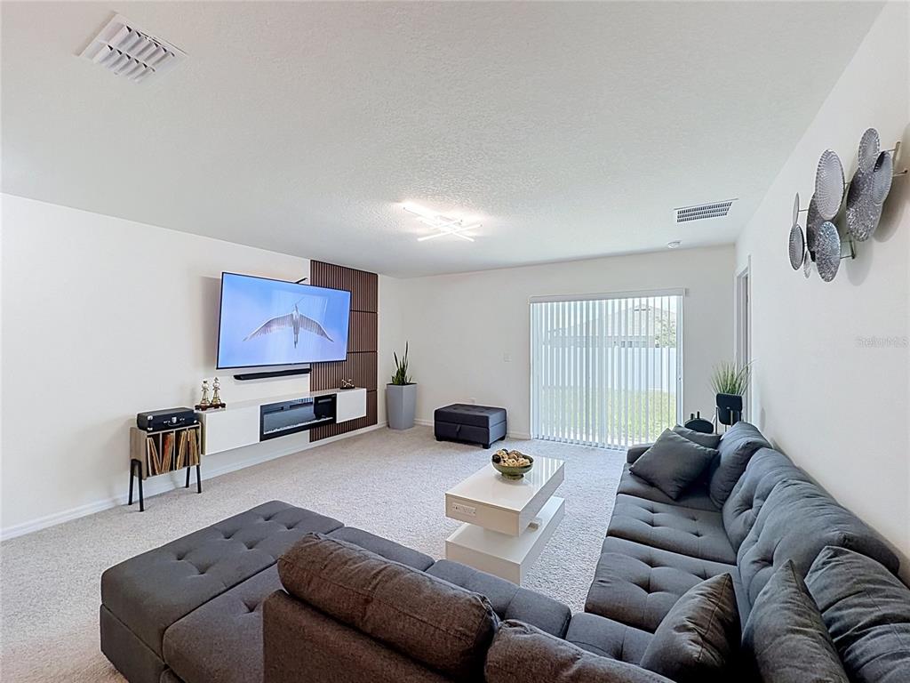 A living room features a grey sectional sofa, a wall-mounted television, and a fireplace console — 339 TOWNS CIRCLE, HAINES CITY, FL