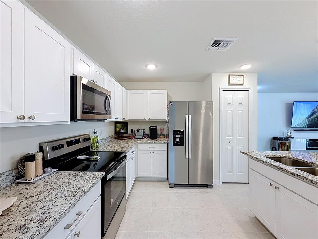 A kitchen features white cabinets, granite countertops, stainless steel appliances, and tile flooring — 339 TOWNS CIRCLE, HAINES CITY, FL
