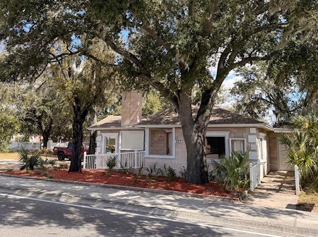 A single-story house with a brick exterior and a chimney sits behind large oak trees — 207 N CHURCH AVENUE UNIT 207, MULBERRY, FL