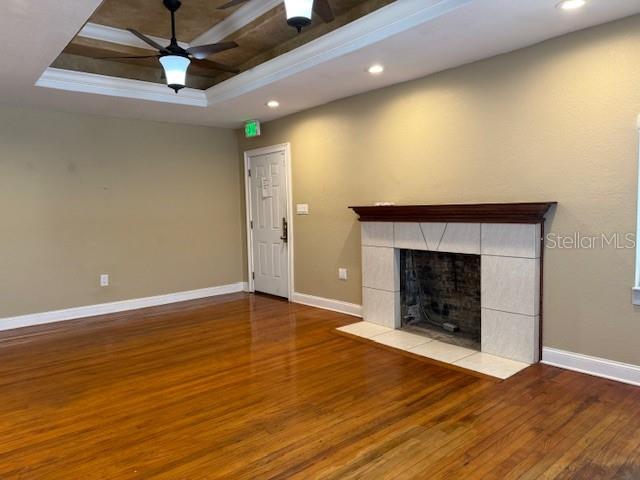 A living room features hardwood floors, a tray ceiling with a fan, and a fireplace — 207 N CHURCH AVENUE UNIT 207, MULBERRY, FL
