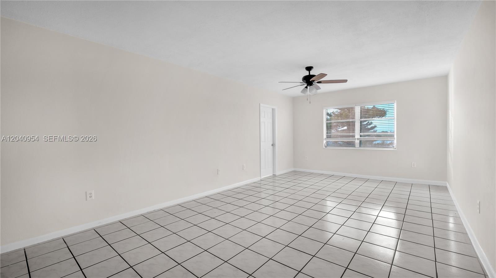 An empty room features white walls, a ceiling fan, and light-colored square floor tiles — 251 NE 187th St # 830, Miami FL 33179, MIAMI, FL