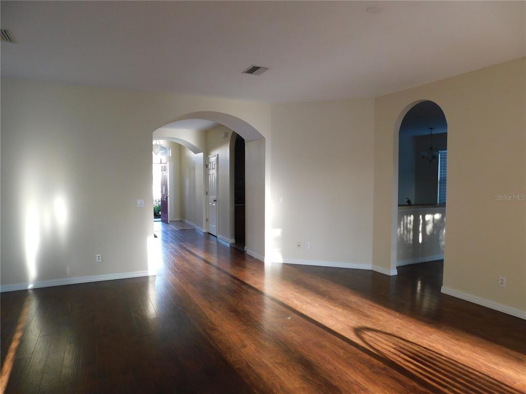 An interior view shows a room with hardwood floors, arched doorways, and light-colored walls — 2507 HOBBLEBRUSH DRIVE, NORTH PORT, FL