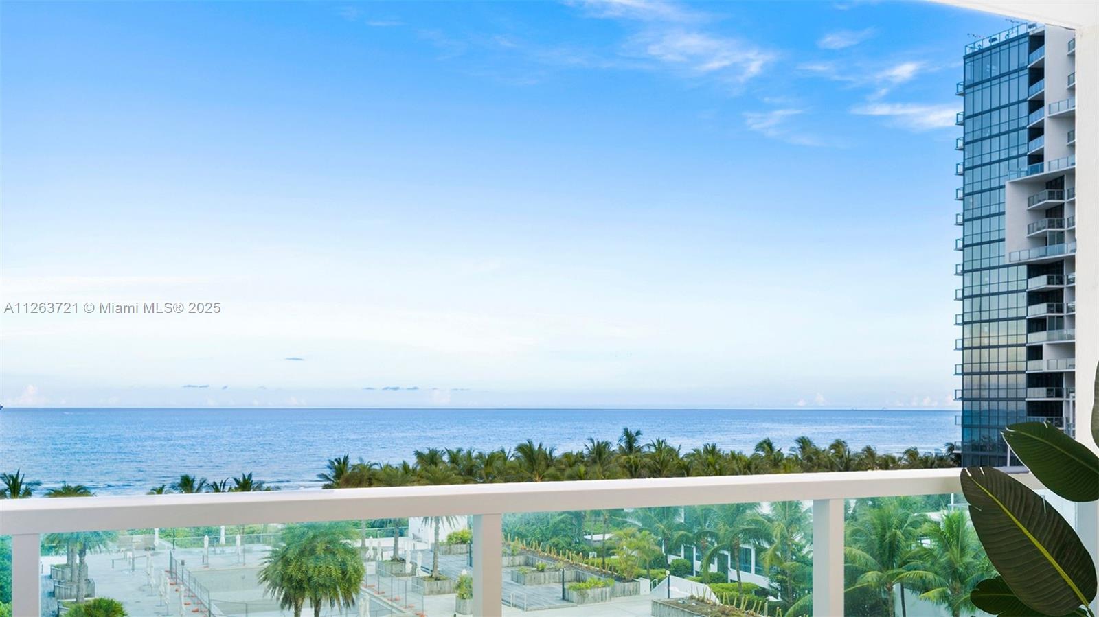A balcony view overlooks a tropical landscape, the ocean, and a neighboring high-rise building — 2301 Collins Ave # 641, Miami Beach FL 33139, MIAMI BEACH, FL