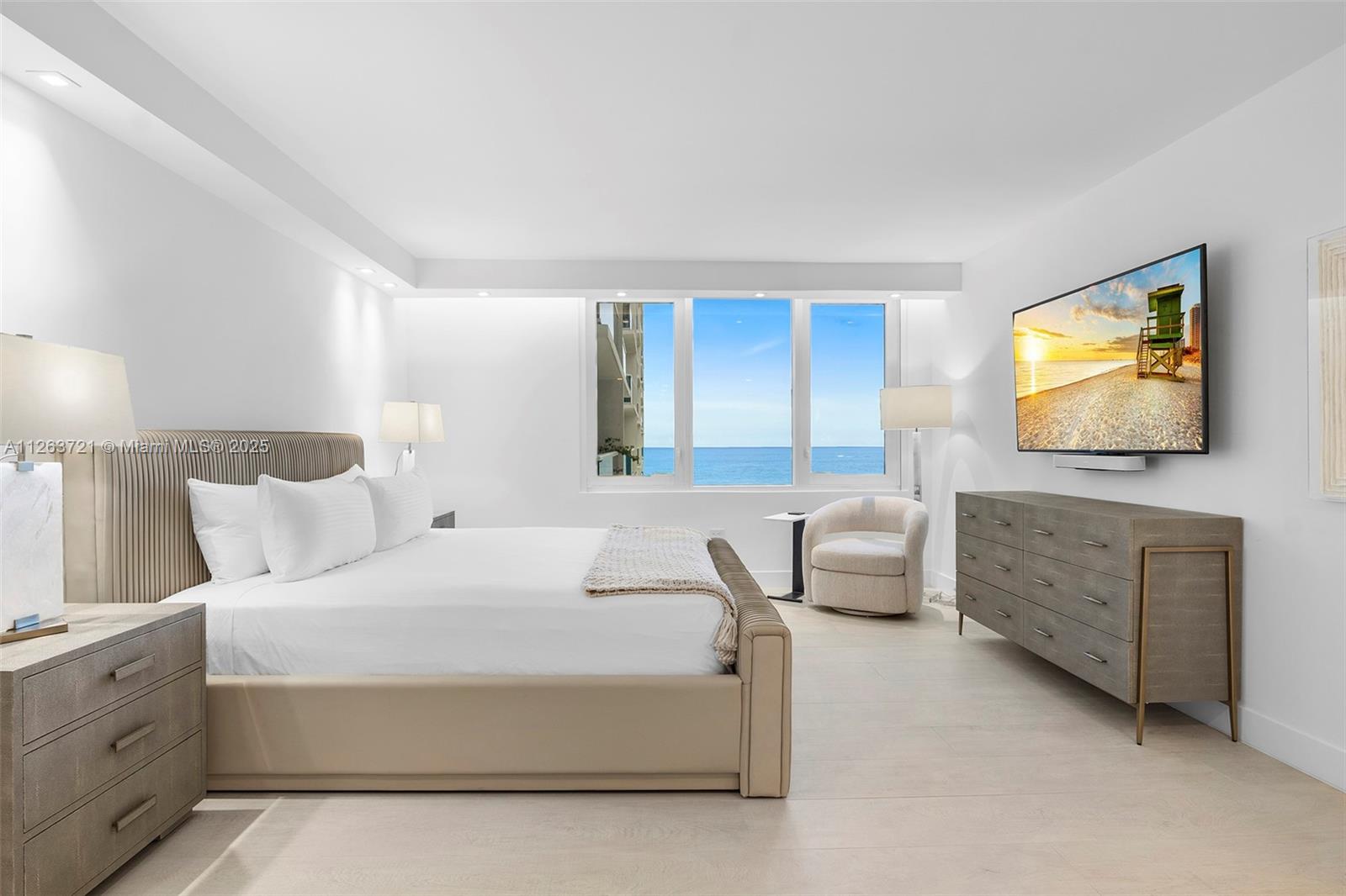A modern bedroom features a king bed, a dresser, and a window overlooking the ocean — 2301 Collins Ave # 641, Miami Beach FL 33139, MIAMI BEACH, FL