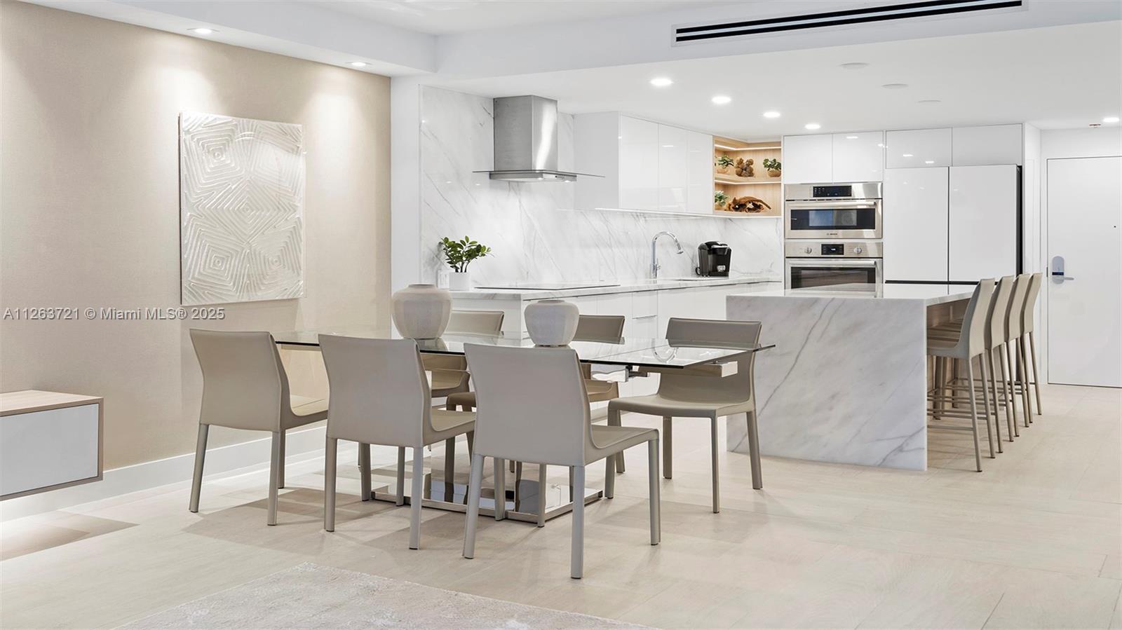 A modern kitchen and dining area feature white cabinetry, marble countertops, and light-colored furniture — 2301 Collins Ave # 641, Miami Beach FL 33139, MIAMI BEACH, FL