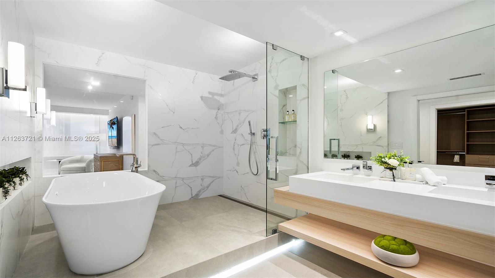 A modern bathroom features a freestanding tub, a glass-enclosed shower, and a floating wood vanity — 2301 Collins Ave # 641, Miami Beach FL 33139, MIAMI BEACH, FL