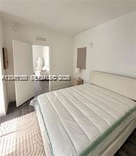 A bedroom features a bed with a white mattress, white walls, and an open doorway — 1525 Euclid Ave # 10, Miami Beach FL 33139, MIAMI BEACH, FL
