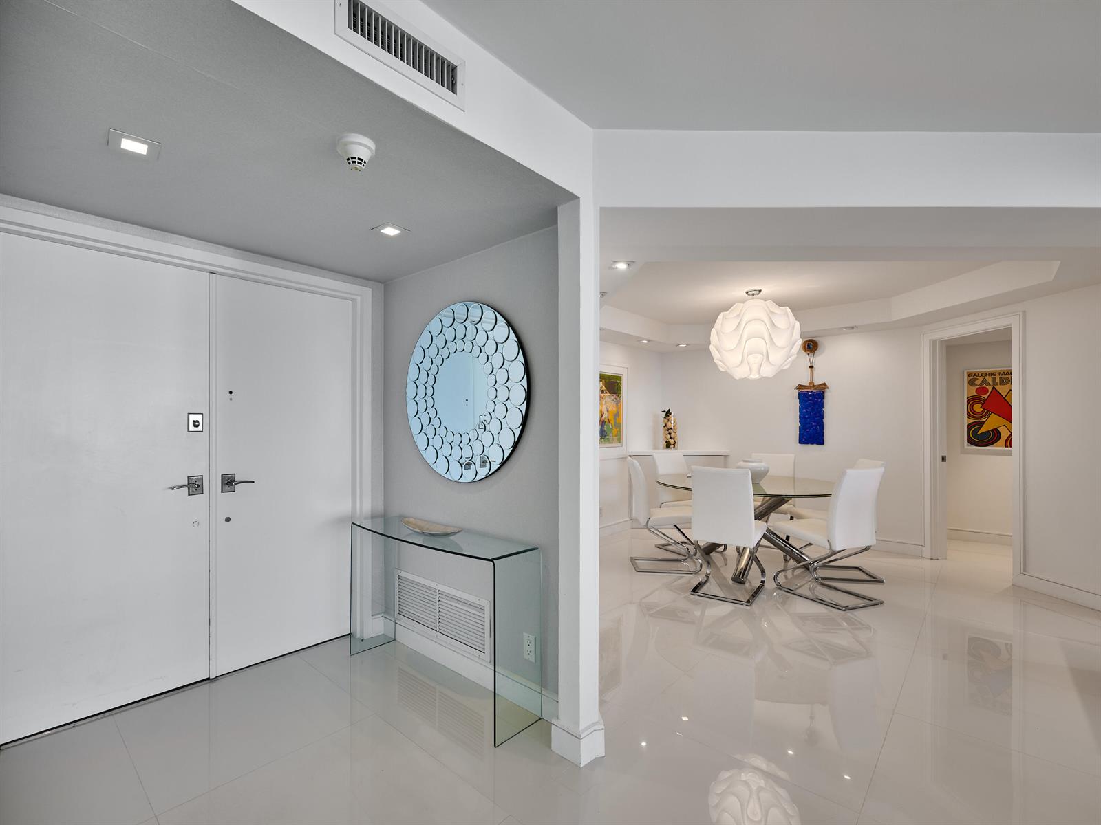 A white-walled entryway with a glass console table leads into a bright dining room — 550 S Ocean Boulevard # 1405, Boca Raton FL 33432, BOCA RATON, FL