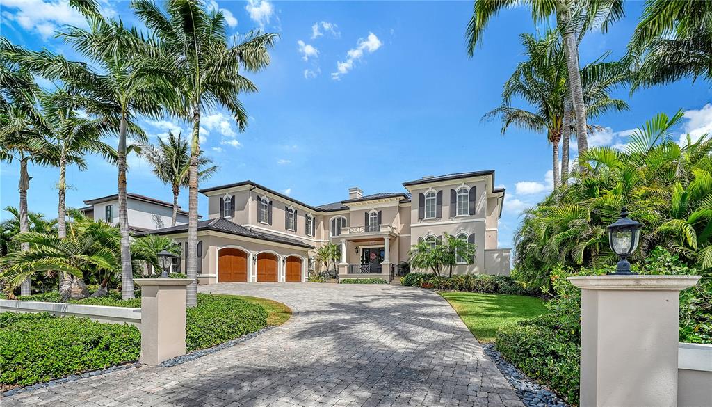 A large two-story house with a stone driveway, three garage bays, and surrounding palm trees — 667 MOURNING DOVE DRIVE, SARASOTA, FL