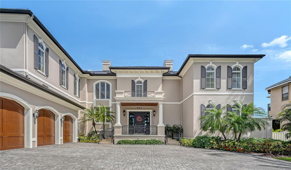 A large, two-story beige house with a stone driveway and a three-car garage — 667 MOURNING DOVE DRIVE, SARASOTA, FL