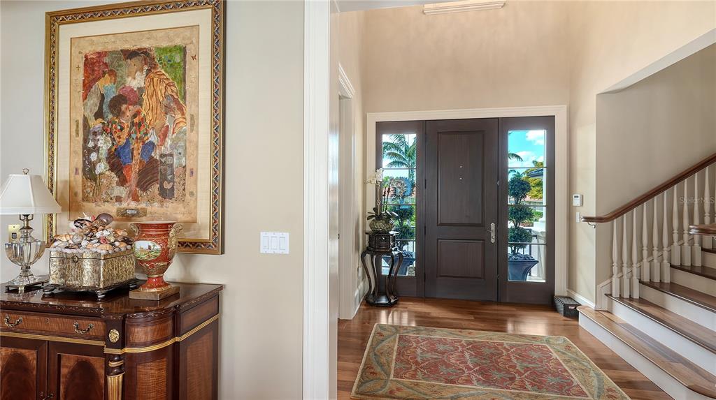 A foyer features a dark wood front door, a staircase, and a decorative console table — 667 MOURNING DOVE DRIVE, SARASOTA, FL