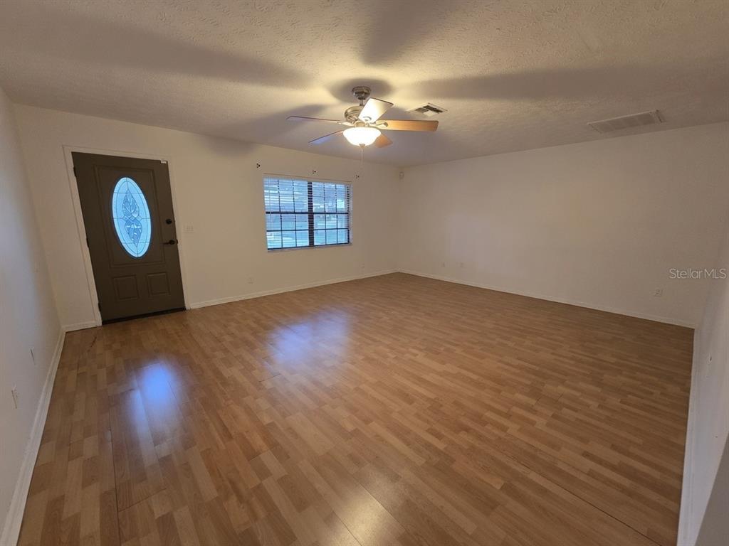 An empty living room features light wood-look flooring, white walls, and a ceiling fan — 202 JACOB RYAN COURT, BRANDON, FL