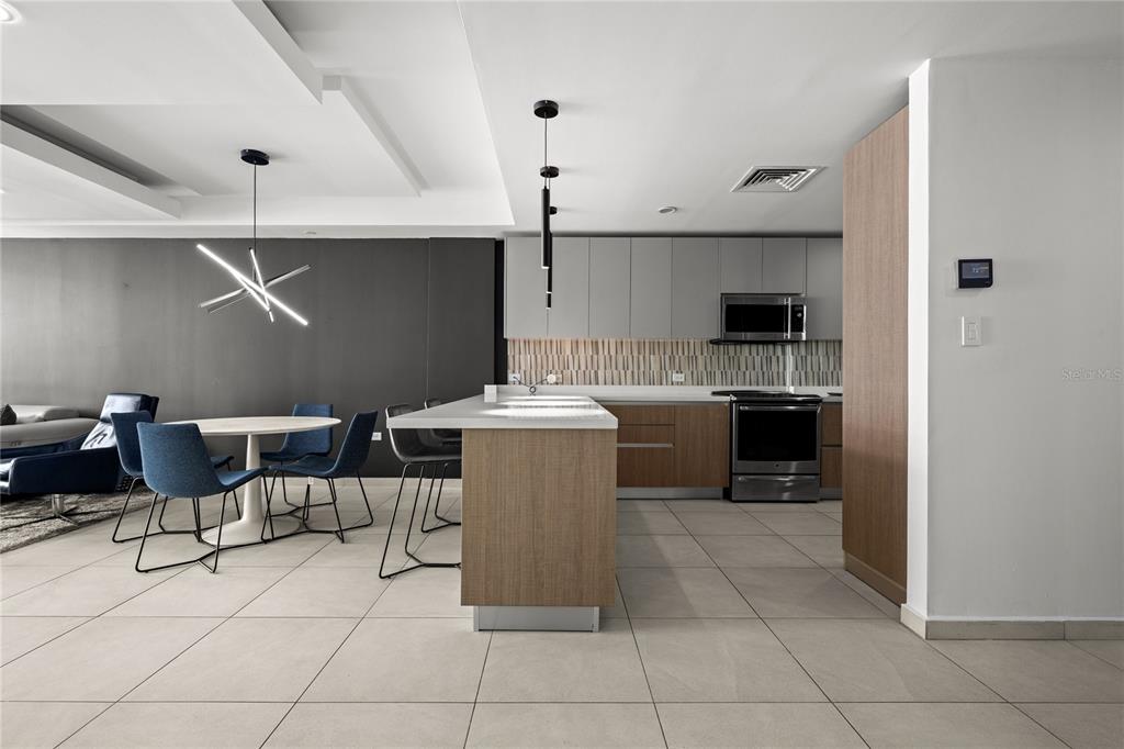 A modern kitchen with wood-toned cabinets, gray upper cabinets, and a white island countertop — 25 Ave Muñoz Rivera BAHIA PLAZA APT UNIT 616, SAN JUAN, PR