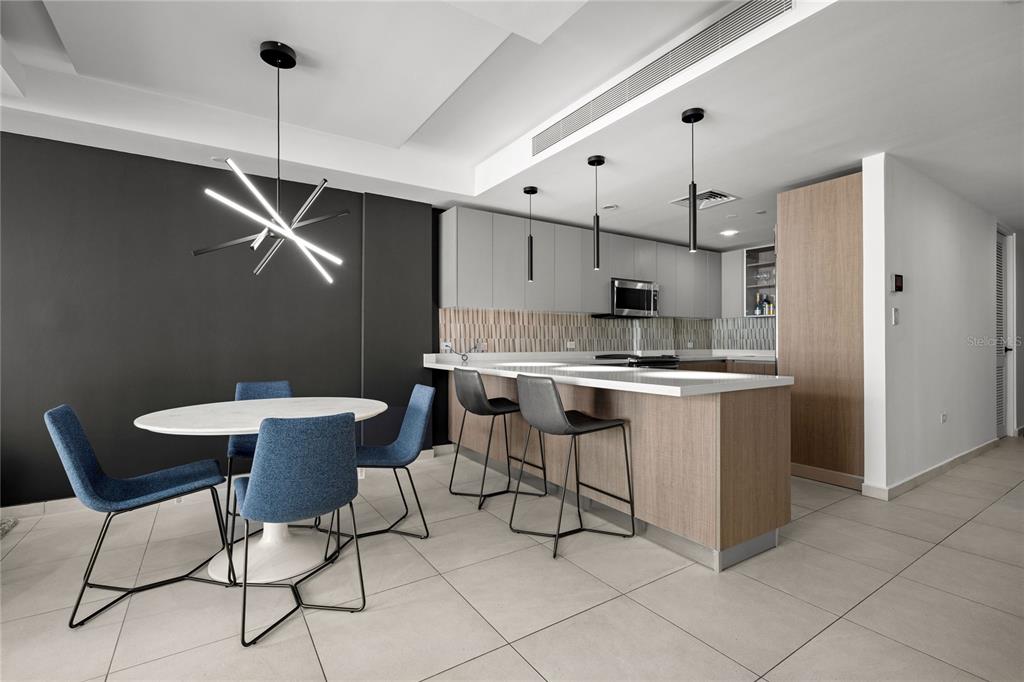 A modern kitchen and dining area with a white island, blue chairs, and gray cabinetry — 25 Ave Muñoz Rivera BAHIA PLAZA APT UNIT 616, SAN JUAN, PR