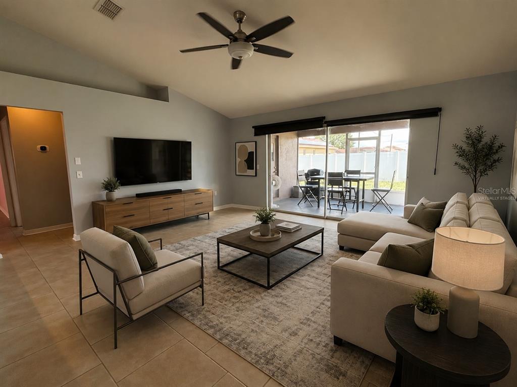 A living room with a television, sofa, armchair, coffee table, and sliding doors to a patio — 20 ANDORA COURT, KISSIMMEE, FL
