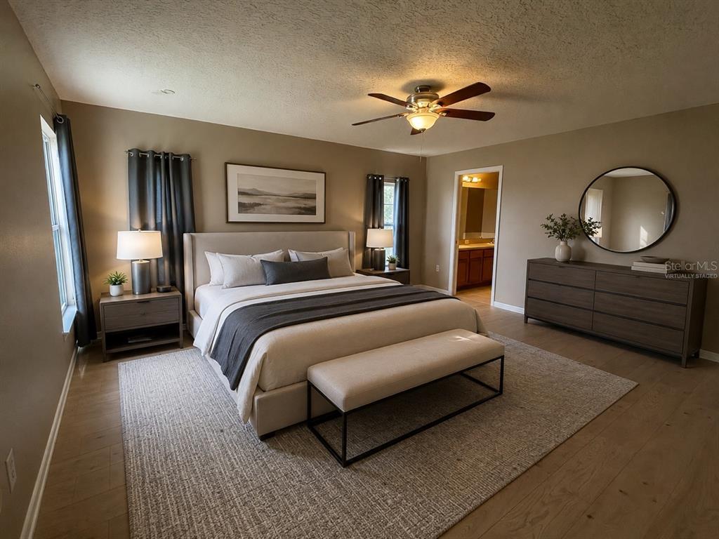 A bedroom features a king-sized bed, a wooden dresser with a round mirror, and hardwood floors — 20 ANDORA COURT, KISSIMMEE, FL