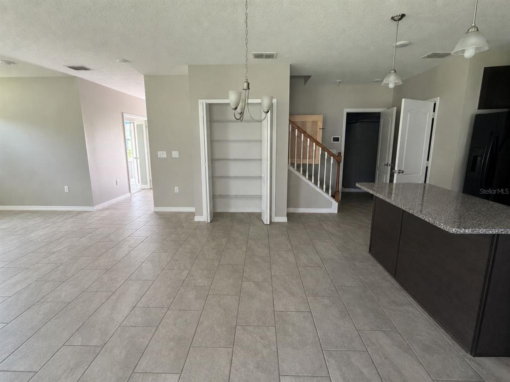 A kitchen and dining area feature tile flooring, a pantry, and a staircase — 100 ALBANY DRIVE, POINCIANA, FL