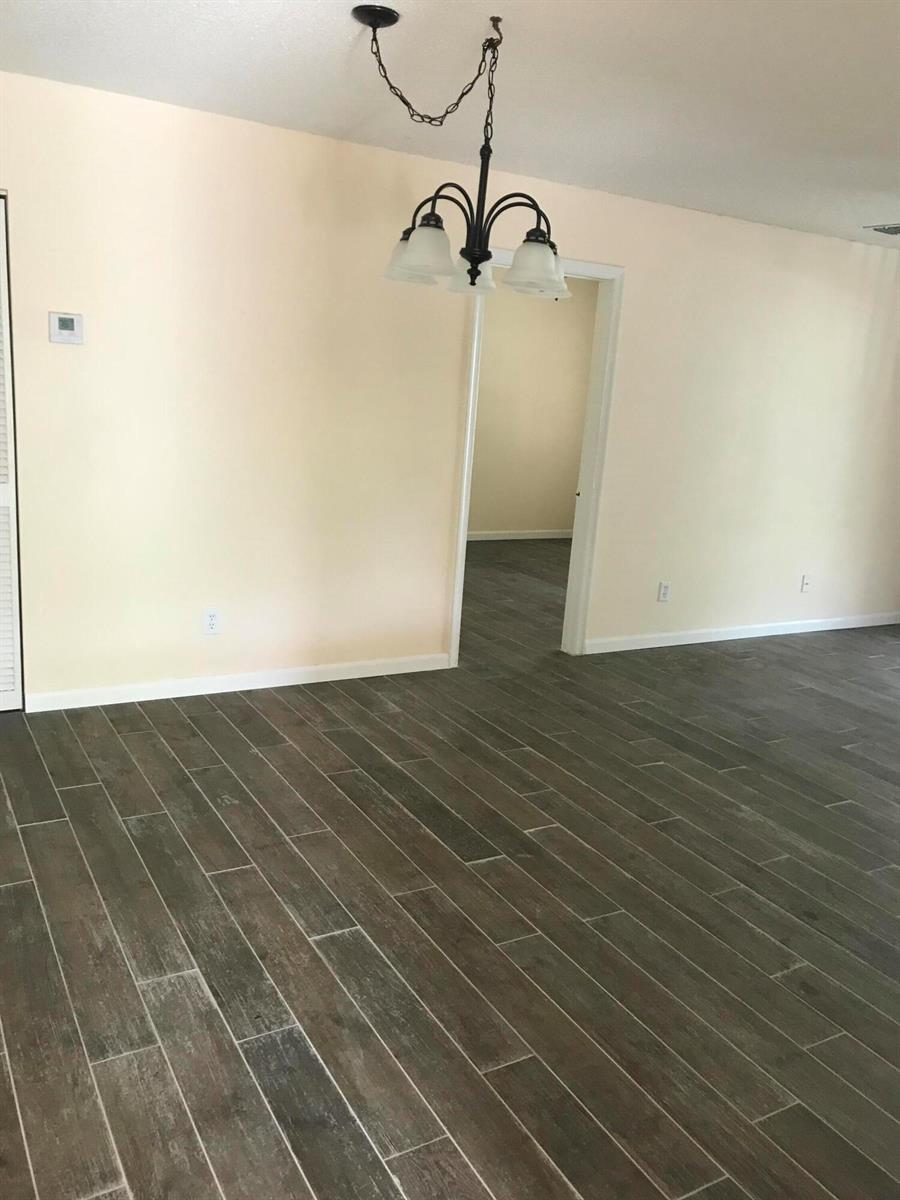 An interior room features wood-look tile flooring, light-colored walls, and a hanging chandelier — 3629 NW 94th Avenue # 5g, Sunrise FL 33351, SUNRISE, FL