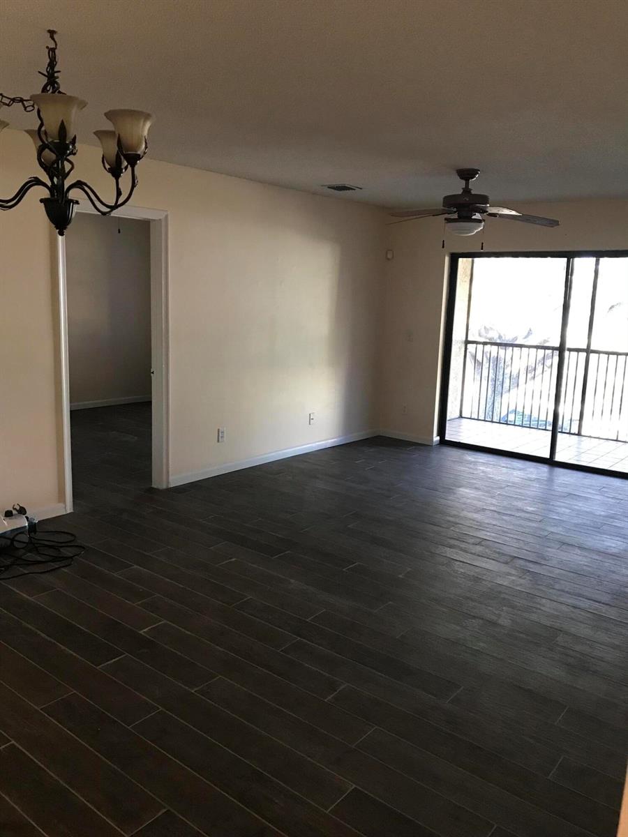 An empty living room features dark wood-look tile flooring, a ceiling fan, and sliding glass doors — 3629 NW 94th Avenue # 5g, Sunrise FL 33351, SUNRISE, FL