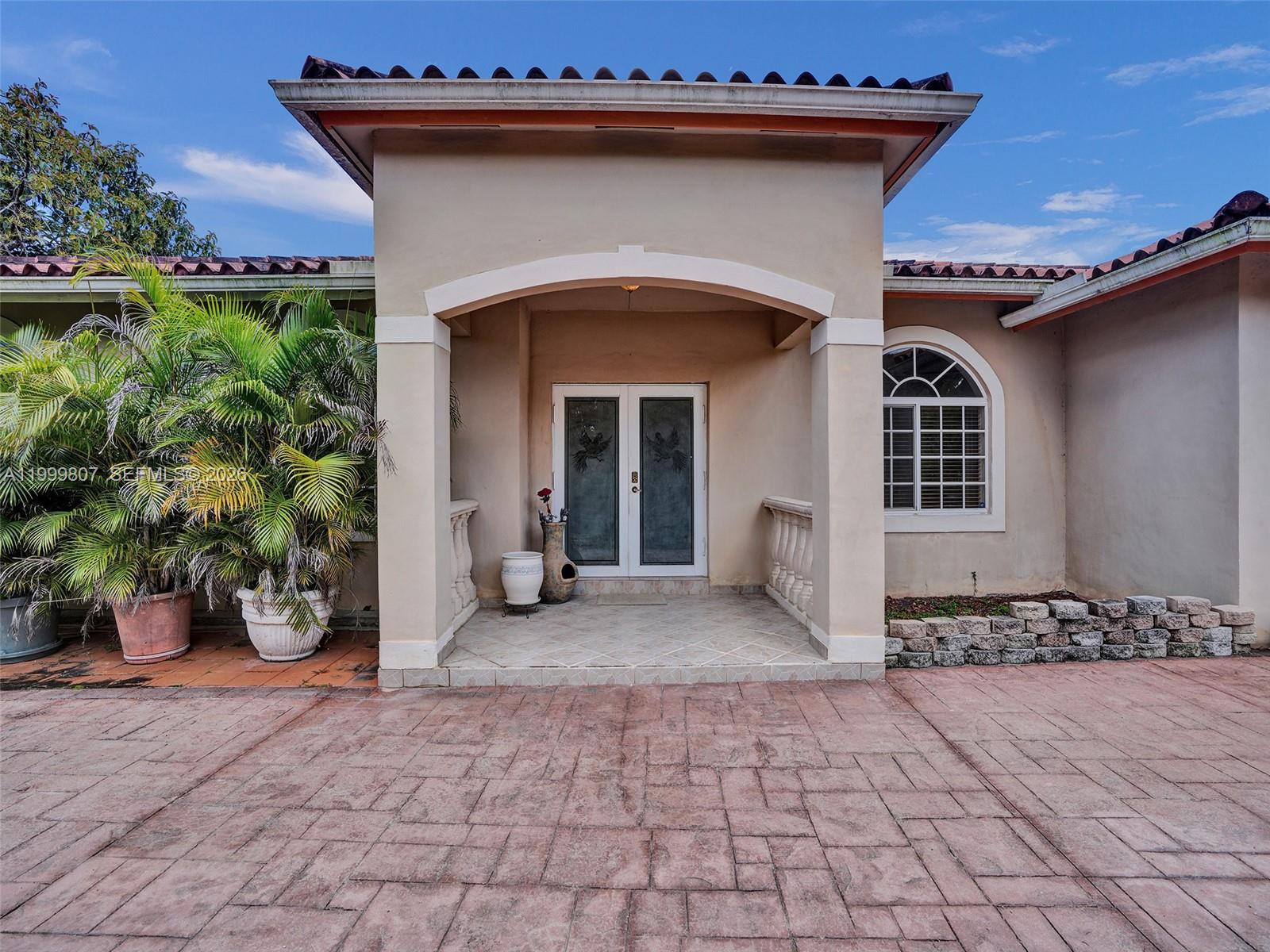The exterior of a house features a covered entryway with double doors and tiled flooring — 23001 SW 167th Ave, Miami FL 33170, MIAMI, FL