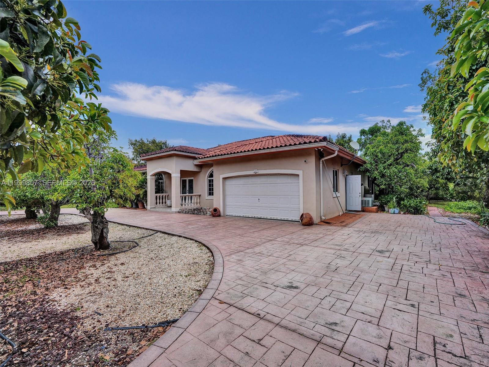 A single-story house with a tiled roof, beige stucco exterior, and a paved driveway — 23001 SW 167th Ave, Miami FL 33170, MIAMI, FL