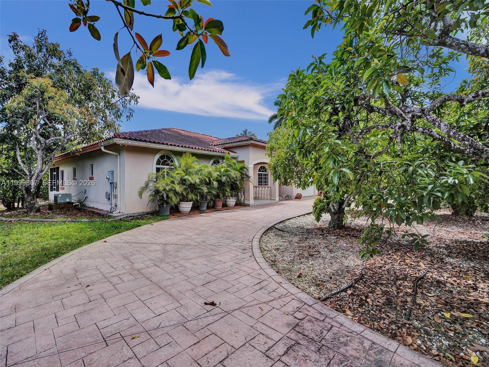 A paved driveway leads to the front entrance of a single-story house with landscaping — 23001 SW 167th Ave, Miami FL 33170, MIAMI, FL