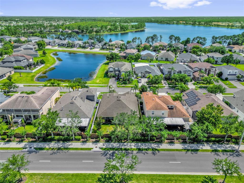 An aerial view shows suburban homes with pools and solar panels near a large lake — 14749 BRUNSWOOD WAY, ORLANDO, FL