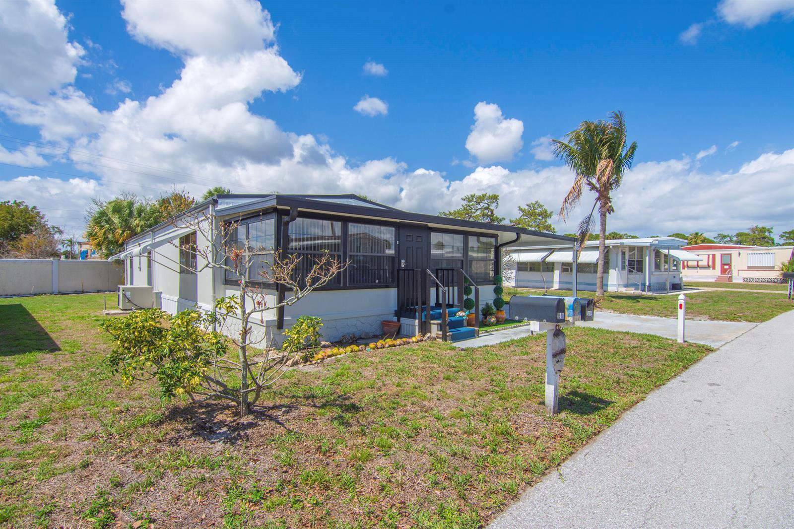 A single-story manufactured home with a dark-trimmed exterior and a small front porch — 2520 SE Penny Lane, Stuart FL 34994, STUART, FL