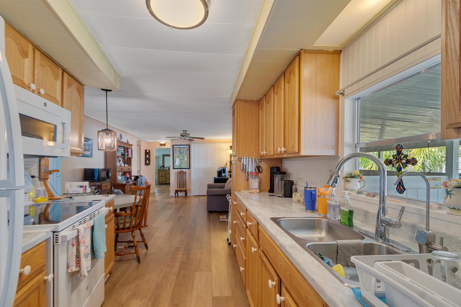 A kitchen with wood cabinets, laminate countertops, and a double sink, opening to a living area — 2520 SE Penny Lane, Stuart FL 34994, STUART, FL