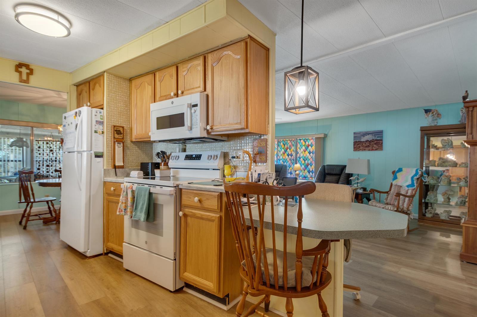A kitchen with wood cabinets, white appliances, and a breakfast bar overlooking a living area — 2520 SE Penny Lane, Stuart FL 34994, STUART, FL