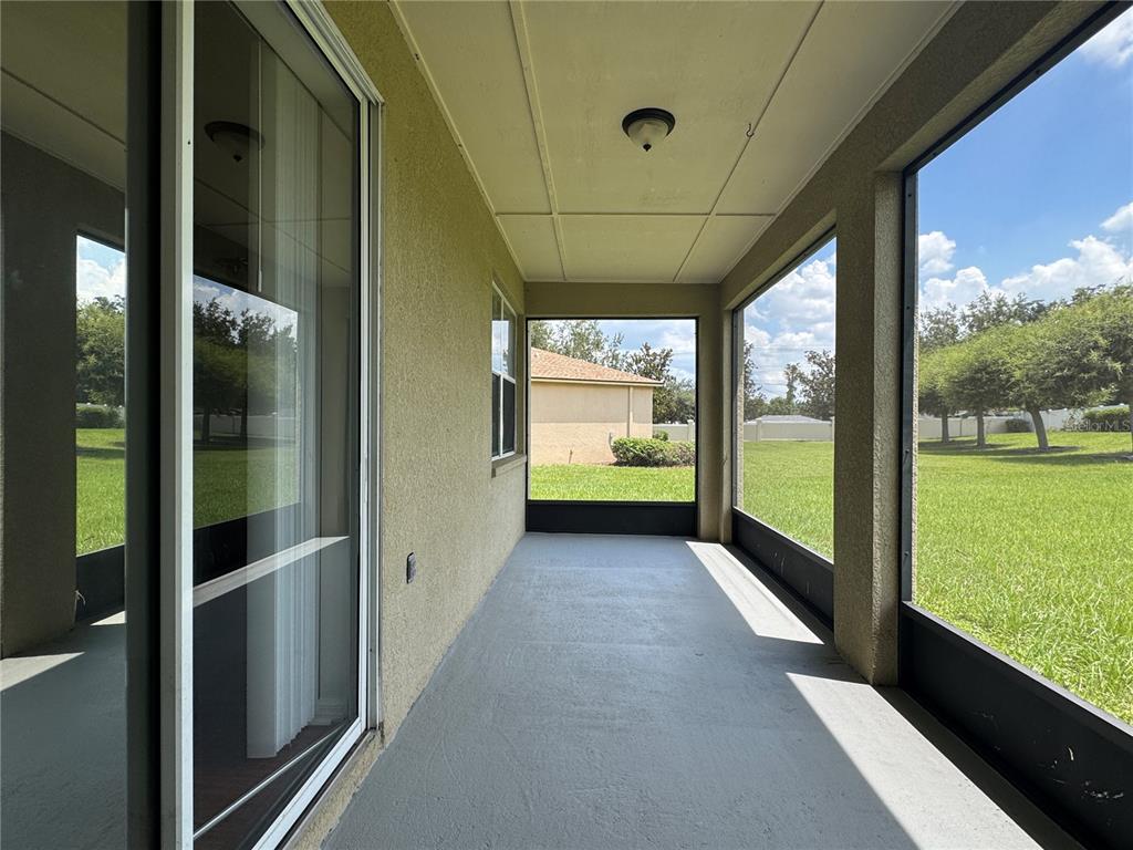 A screened-in porch with a concrete floor, stucco walls, and views of a grassy yard — 317 DOWN PINE DRIVE, SEFFNER, FL
