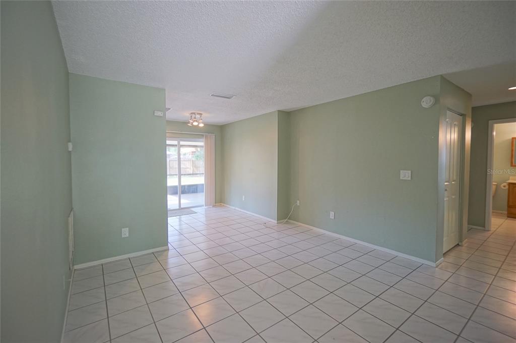 An empty room with light green walls, white tile flooring, and a sliding glass door — 5117 ELLENDALE AVENUE, TAMPA, FL