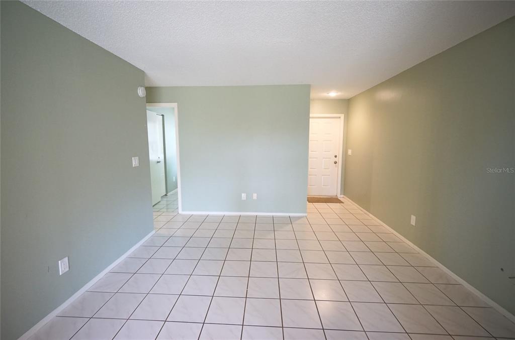 An empty room features light green walls, white tile flooring, and a white front door — 5117 ELLENDALE AVENUE, TAMPA, FL