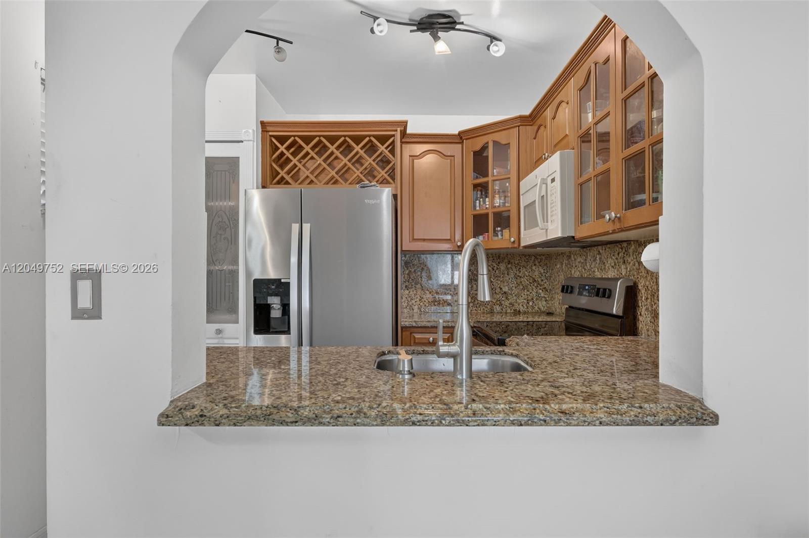 A kitchen features granite countertops, wood cabinets, stainless steel appliances, and a pass-through opening — 14929 SW 104th St # 14, Miami FL 33196, MIAMI, FL