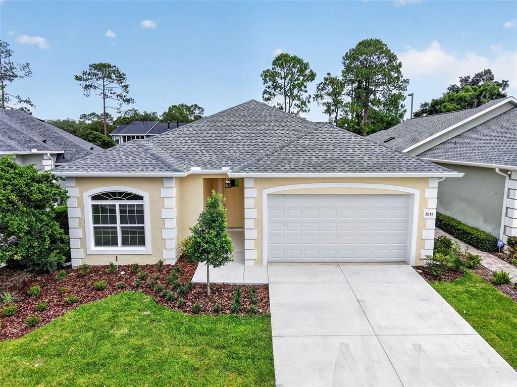 A single-story house with a yellow stucco exterior, a two-car garage, and a shingled roof — 3045 SW 41ST PLACE, OCALA, FL