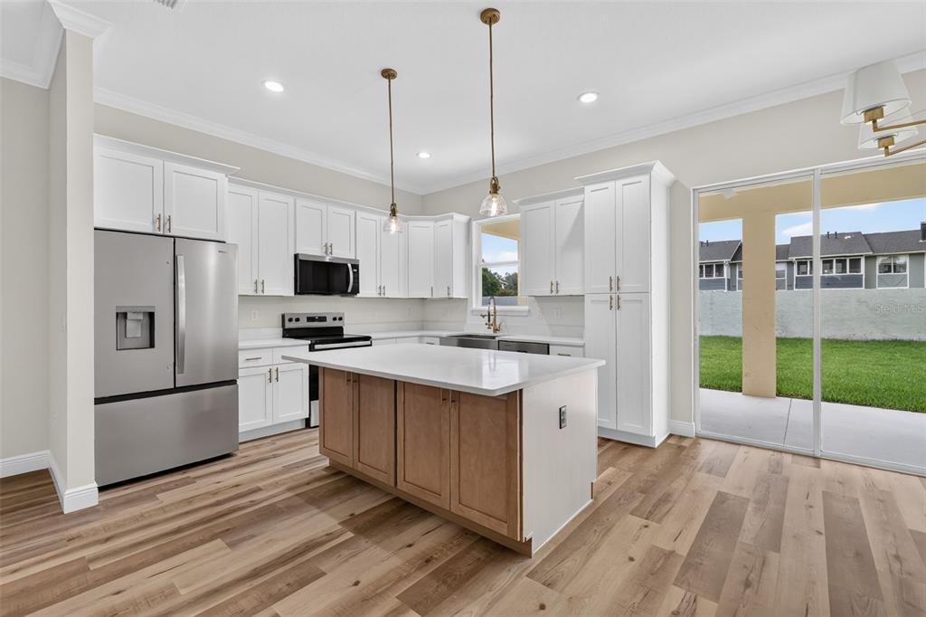 A kitchen with white cabinets, a wood-toned island, stainless steel appliances, and a sliding door — 3045 SW 41ST PLACE, OCALA, FL