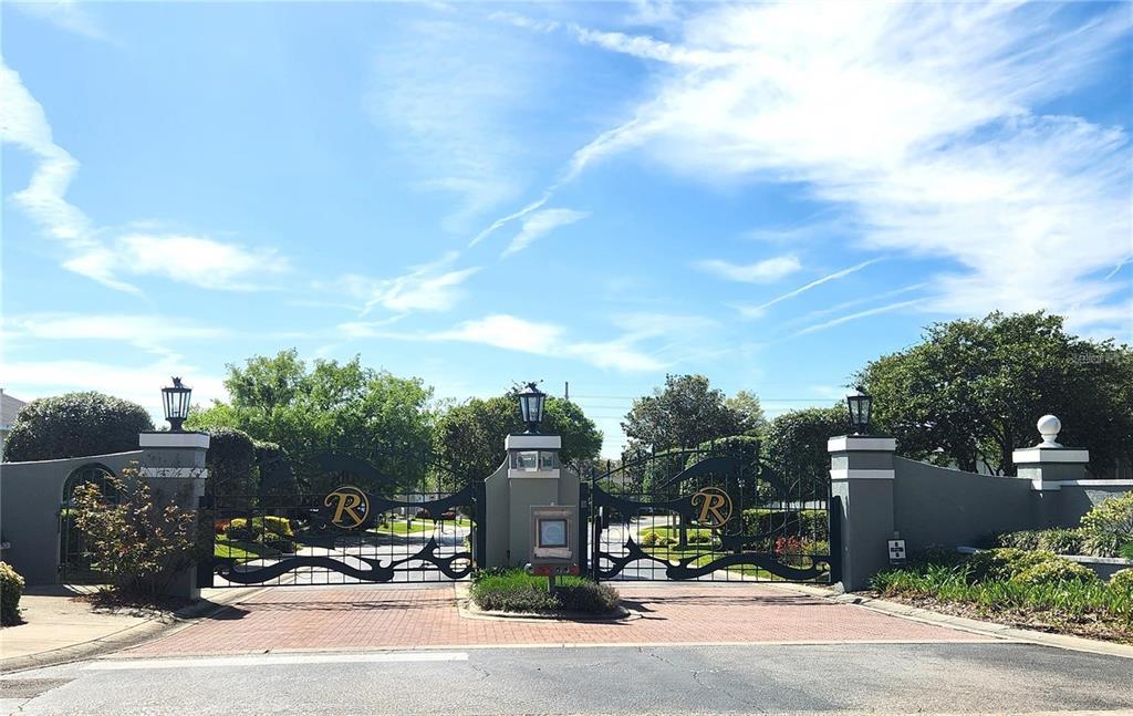 A gated entrance with decorative metal gates and stone pillars under a blue sky — 3045 SW 41ST PLACE, OCALA, FL