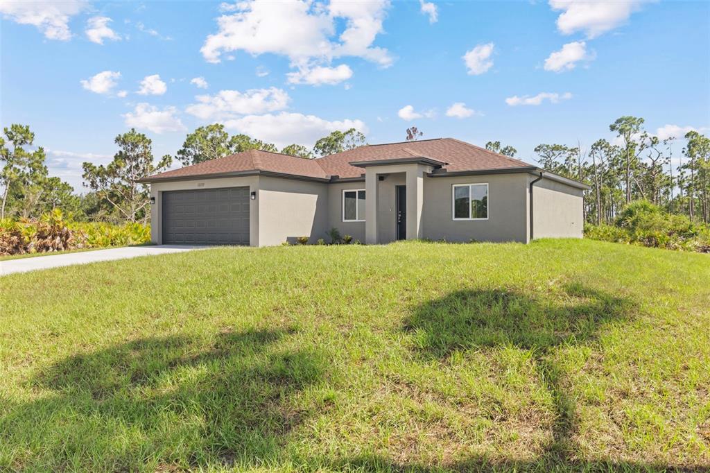 A single-story house with a gray stucco exterior, a brown roof, and a two-car garage — 12233 WAGNER LANE, PORT CHARLOTTE, FL