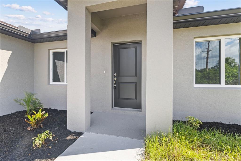 The exterior entrance features a dark gray door framed by two large, light-colored stucco pillars — 12233 WAGNER LANE, PORT CHARLOTTE, FL