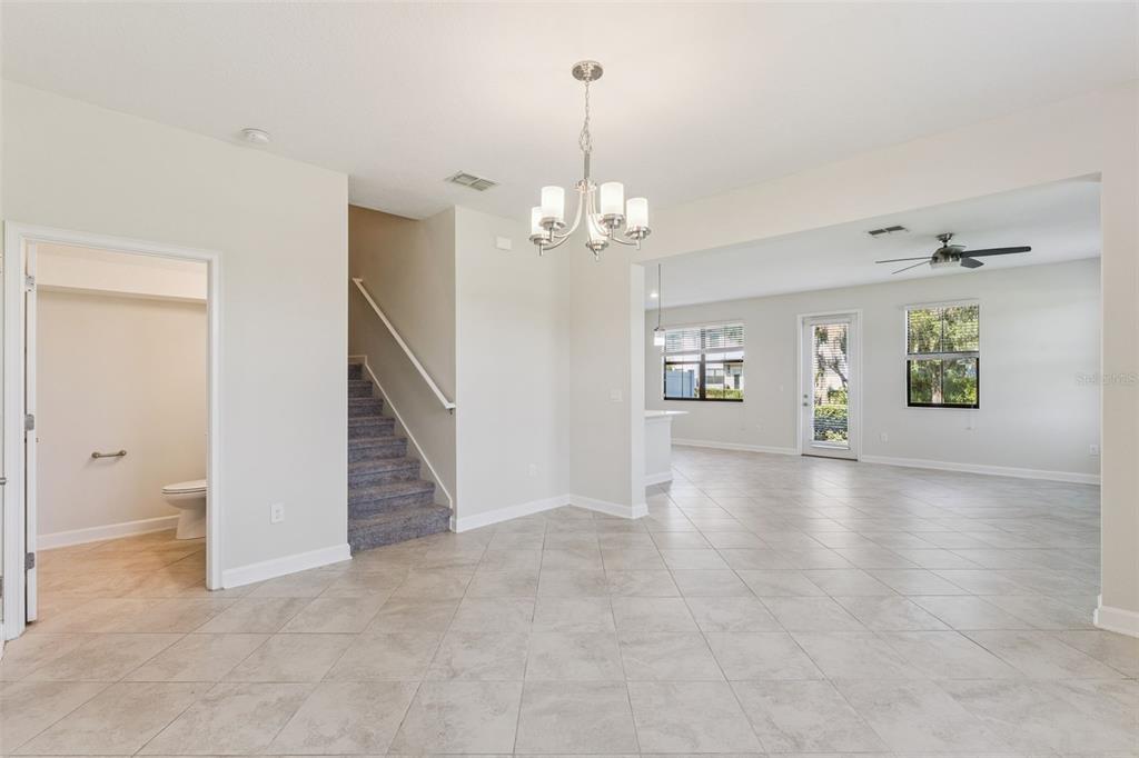 An open-concept living area features tile flooring, a staircase, and a chandelier — 11433 WHISTLING PINE WAY, ORLANDO, FL