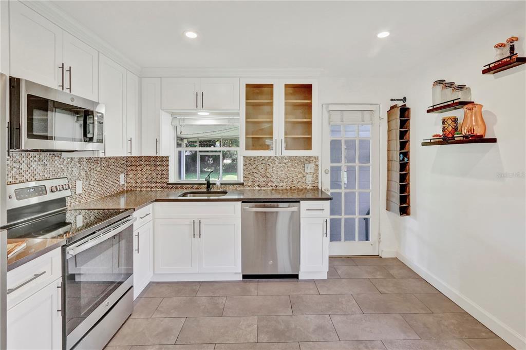 A kitchen with white cabinets, stainless steel appliances, a mosaic tile backsplash, and tile flooring — 1016 W SMITH STREET, ORLANDO, FL