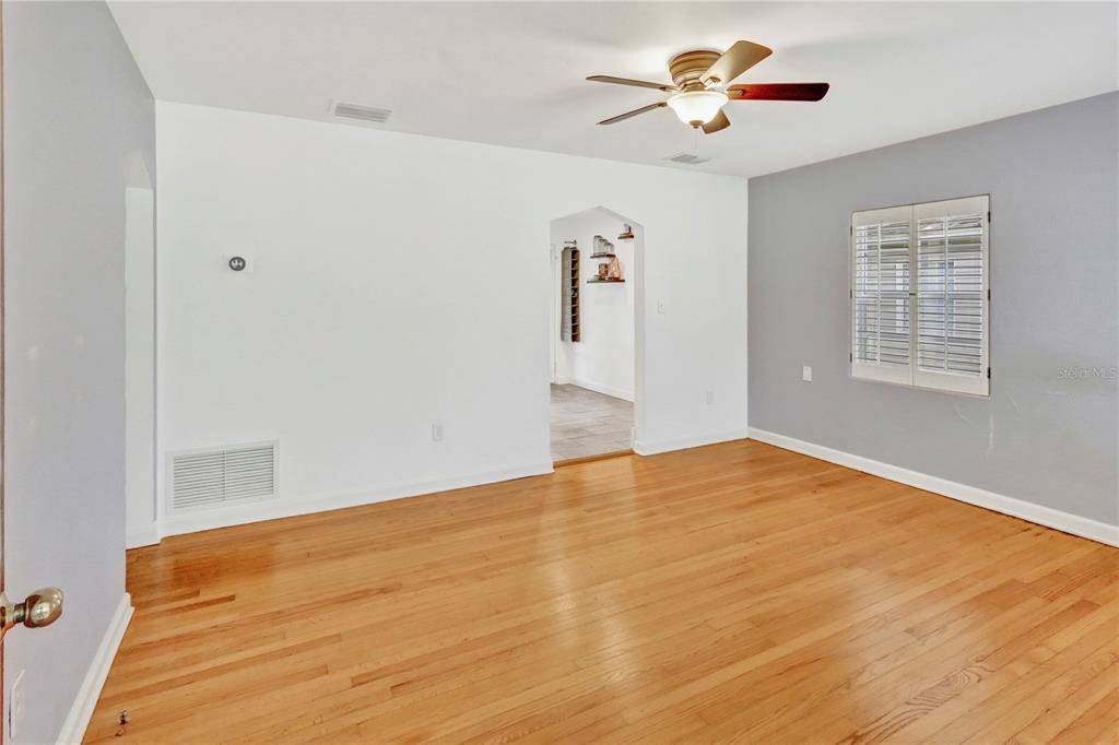 An empty living room features hardwood floors, white walls, a gray accent wall, and ceiling fan — 1016 W SMITH STREET, ORLANDO, FL