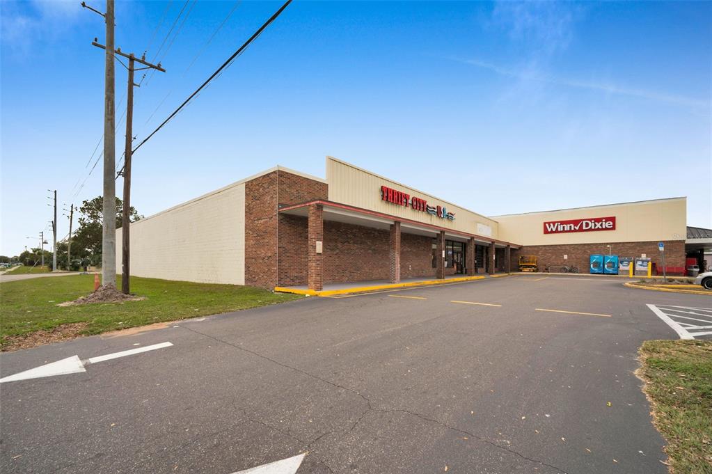 An exterior view of a commercial strip mall featuring a Thrift City and Winn-Dixie store — 5802 54TH AVENUE N, KENNETH CITY, FL