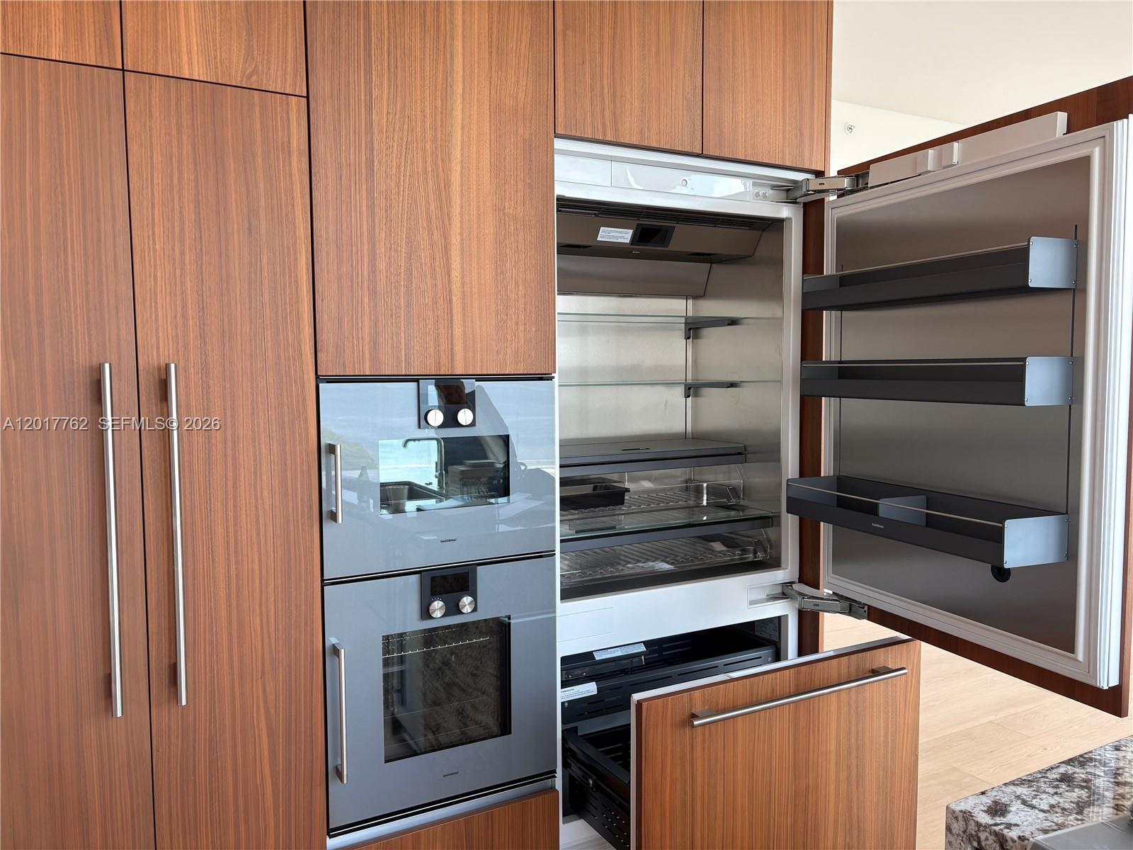 A modern kitchen features wood-paneled cabinetry, integrated appliances, and a built-in refrigerator — 175 SE 25 Road # 602, Miami FL 33129, MIAMI, FL