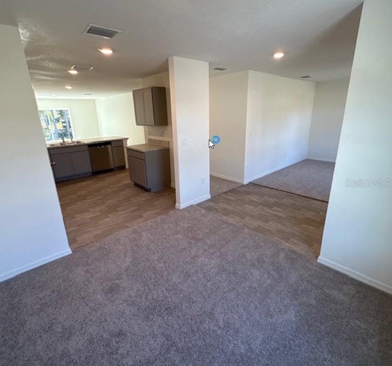 An interior view shows a kitchen with gray cabinets and adjacent carpeted living areas — 42 PEPPERCORN LANE, PALM COAST, FL