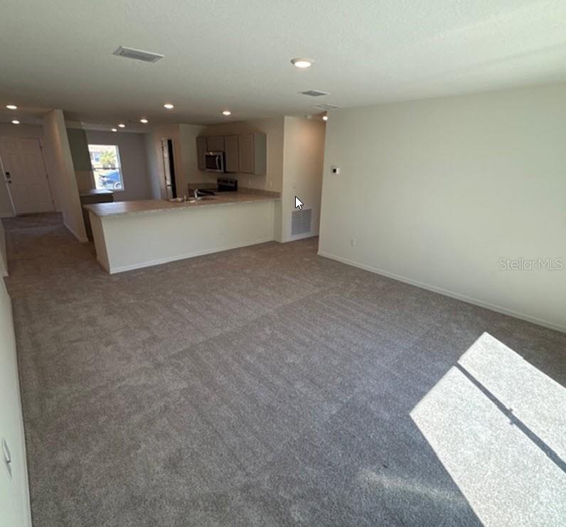 An open-concept living area features gray carpeting and a kitchen with a breakfast bar — 42 PEPPERCORN LANE, PALM COAST, FL