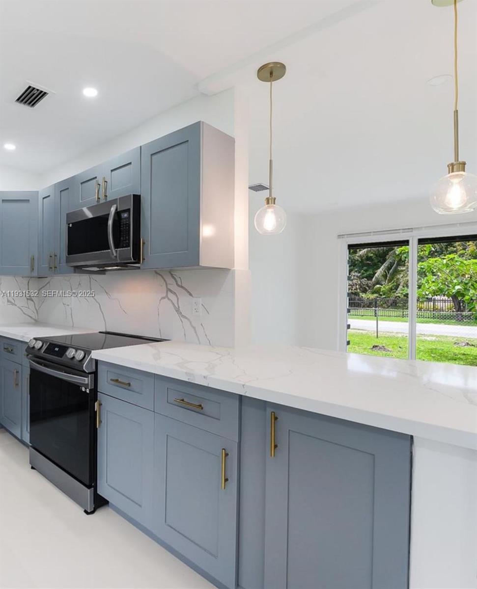 A kitchen features blue cabinets, white marble countertops, and two pendant lights over a counter — 851 NW 146th St, Miami FL 33168, MIAMI, FL